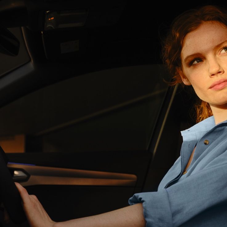 EIne Frau sitzt bei geöffneter Fahrertür am Steuer eines CUPRA Formentor