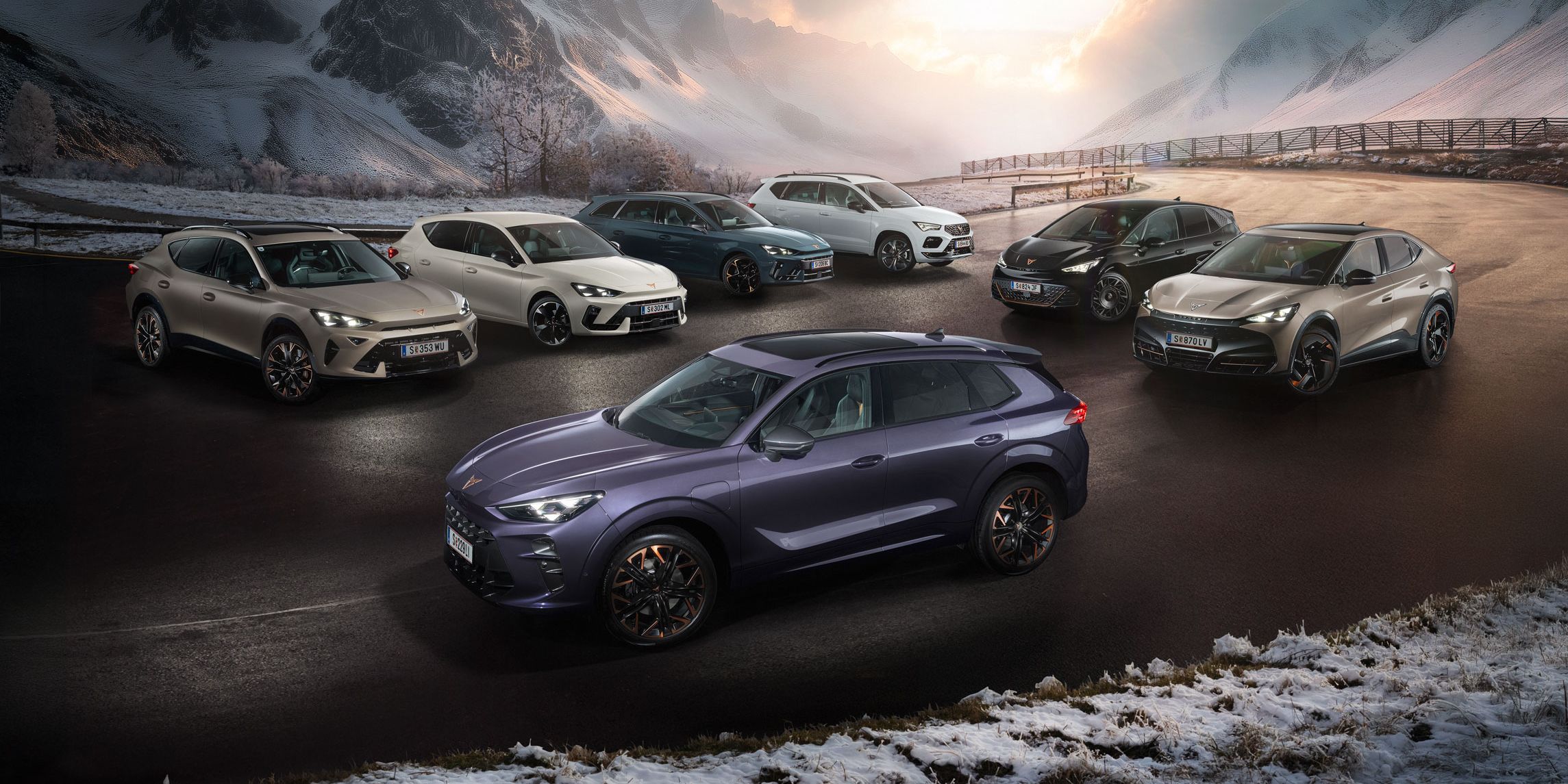 Eine Gruppe von CUPRA Fahrzeugen stehen auf einer verschneiten Straße vor einer malerischen Berglandschaft bei Sonnenuntergang. Es sind verschiedene Modelle in unterschiedlichen Farben. Im Hintergrund sind hohe, schneebedeckte Berge und dramatische Wolkenformationen zu sehen.