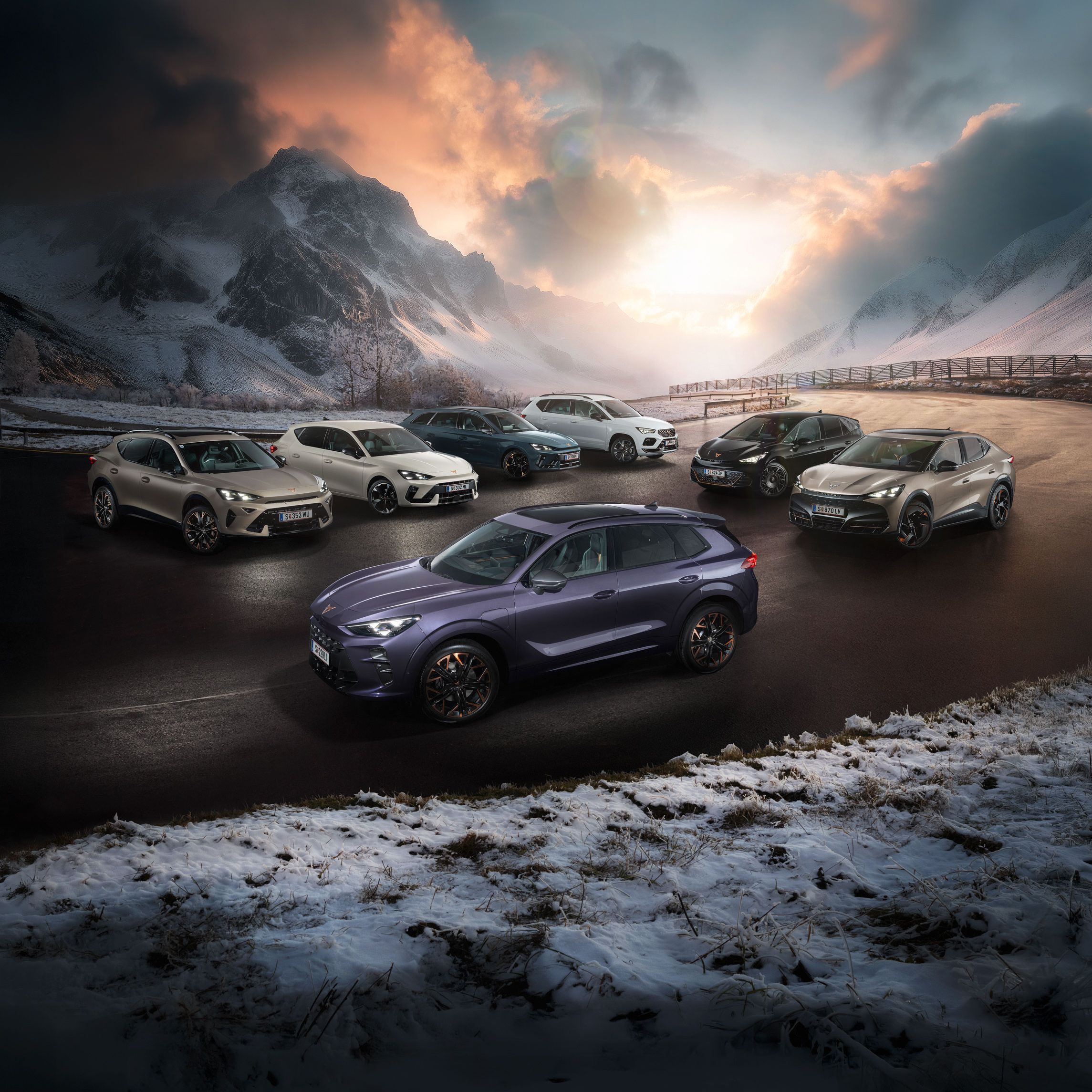 Eine Gruppe von CUPRA Fahrzeugen stehen auf einer verschneiten Straße vor einer malerischen Berglandschaft bei Sonnenuntergang. Es sind verschiedene Modelle in unterschiedlichen Farben. Im Hintergrund sind hohe, schneebedeckte Berge und dramatische Wolkenformationen zu sehen.