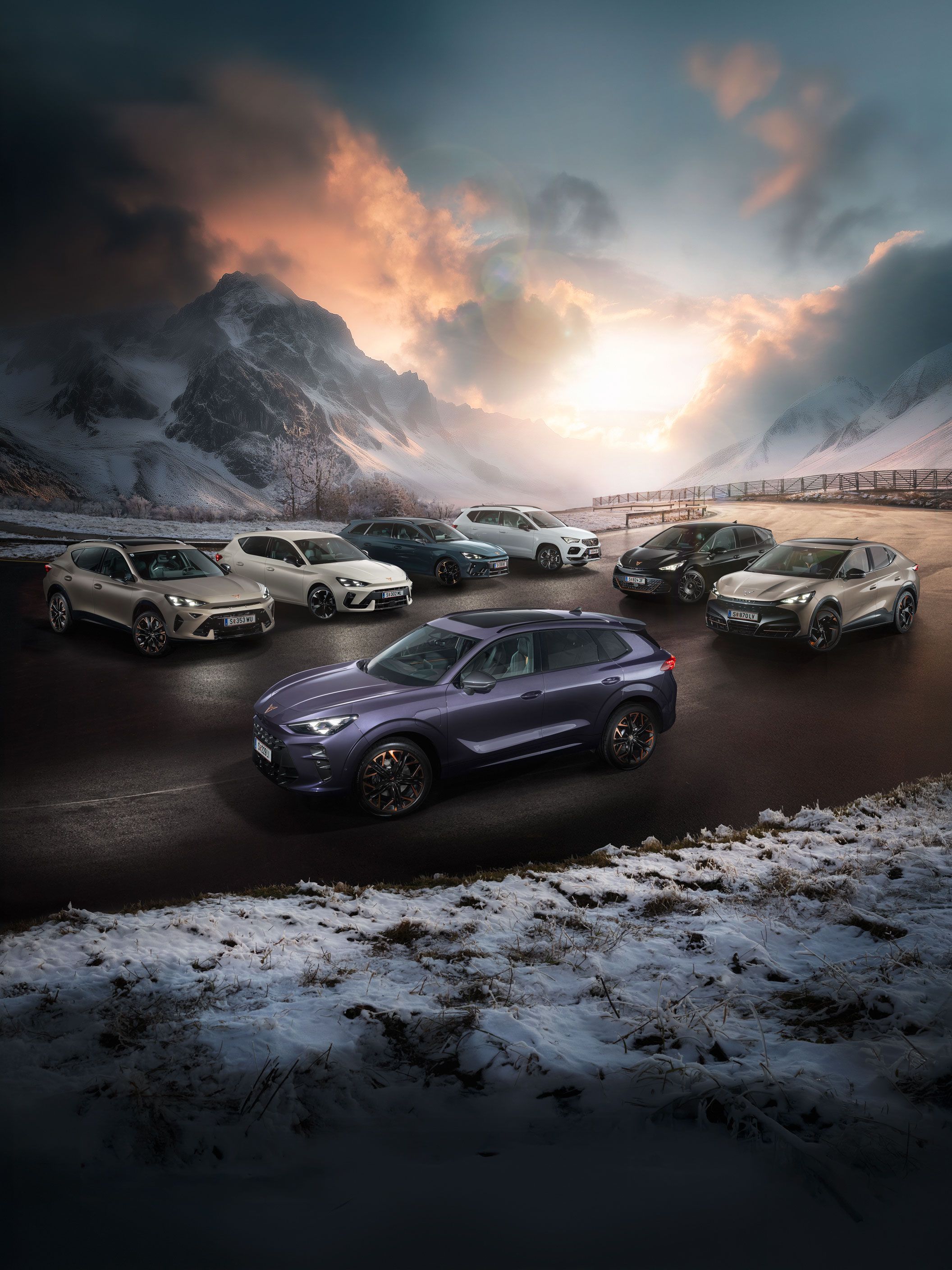 Eine Gruppe von CUPRA Fahrzeugen stehen auf einer verschneiten Straße vor einer malerischen Berglandschaft bei Sonnenuntergang. Es sind verschiedene Modelle in unterschiedlichen Farben. Im Hintergrund sind hohe, schneebedeckte Berge und dramatische Wolkenformationen zu sehen.
